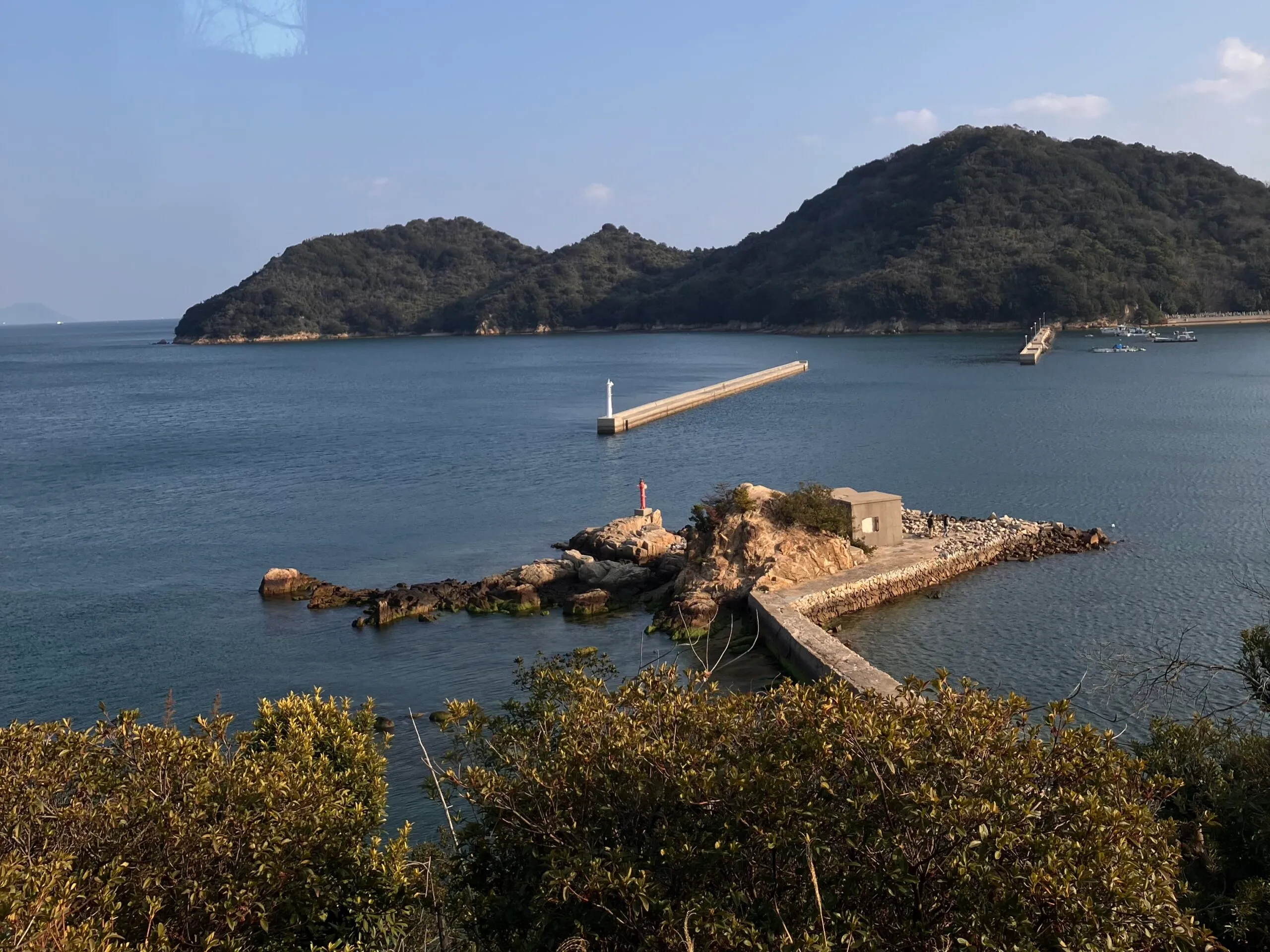 瀬戸内海の入り江に伸びる防波堤と、対岸の島影